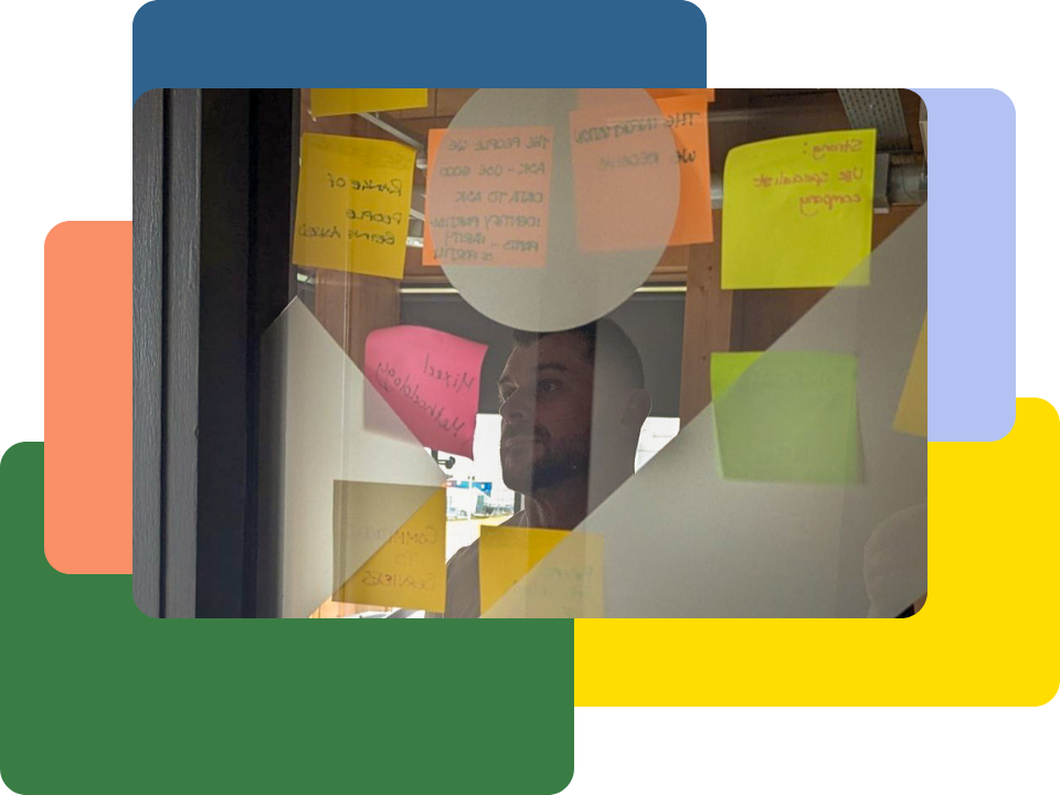 A view through frosted glass showing a man looking at sticky notes on the other side during a workshop.
